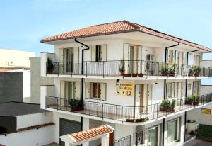 un edificio bianco con balconi e piante di Fragolina B&B a Furci Siculo