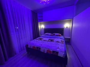 a purple bedroom with a bed in a room with windows at Стильна квартира в новому будинку, поряд центр та р. Дніпро in Cherkasy