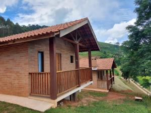 a brick house with a porch and a balcony at Chalés Santa Luzia in Santo Antônio do Pinhal