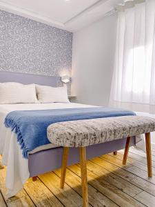 a bedroom with a bed with a blue blanket and a bench at Filipe Village - Casa da Índia in Sesimbra