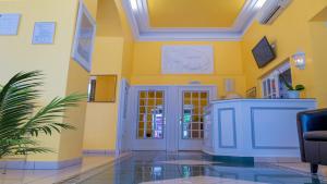 eine Lobby mit gelben Wänden und einer weißen Tür in der Unterkunft Hotel Berlioz Basel Airport in Saint-Louis