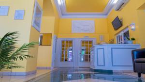 a lobby with yellow walls and a white door at Hotel Berlioz Basel Airport in Saint-Louis