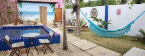 um pátio com uma rede de descanso, uma mesa e cadeiras em Frida Hostel em Jericoacoara