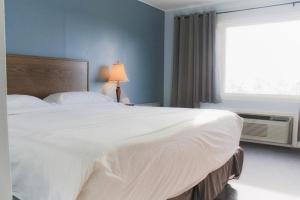 Un dormitorio con una gran cama blanca y una ventana en Carolyn Beach Inn, en Thessalon