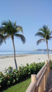 two palm trees and a beach with a wooden fence at Mayan Vidanta Villas GOLF a 800 mt de la playa in Acapulco