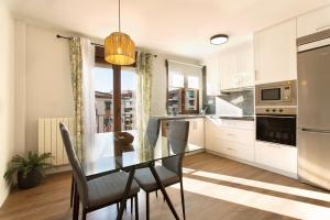 Una cocina con una mesa de cristal y sillas. en Apartamento Zoraida Centro, en Granada