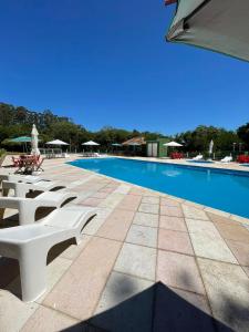 a swimming pool with white benches next to a building at Pousada Esperança in Osório