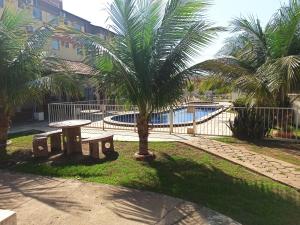 a park with a table and palm trees and a pool at Apto dois quartos, cozinha equipada, portaria 24 h, área de lazer in Imperatriz