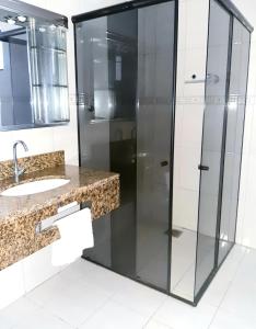 a glass shower in a bathroom with a sink at Hotel Cantinho Verde in Teixeira de Freitas