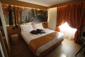 a bedroom with a large bed with a painting on the wall at Hotel Petit Tournalin in Champoluc