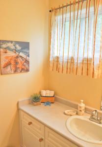 een badkamer met een wastafel en een raam bij Wild Pacific Guest Suites in Ucluelet