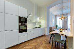 una cocina con armarios blancos y una mesa con sillas. en Central Basilica Apartman, en Budapest