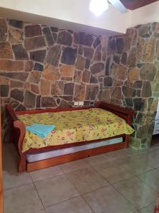 Ce lit se trouve dans un dortoir doté d'un mur en pierre. dans l'établissement Apart JM, à Puerto Iguazú