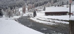 a river with snow on it next to a building at Lago Rotondo Ski House in Mezzana