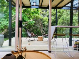 a room with a porch with chairs on a deck at Blackwood Cabin in Raglan