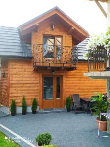 a wooden house with a balcony and a table at Domek Fafik in Krościenko