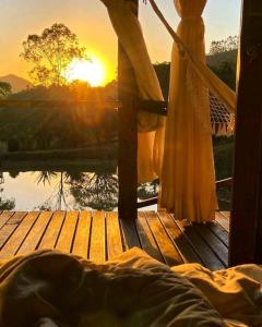 a bed on a wooden deck with the sunset in the background at Pousada Caminho dos Ipês in Bocaina de Minas