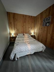 a bedroom with a large bed with wooden walls at Le cocon des Nestes in Arreau
