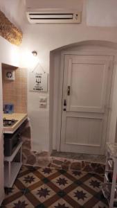 cocina con puerta blanca y suelo de baldosa en La Casetta del Tufo, en Matino