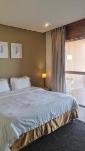 una camera da letto con un grande letto bianco e una finestra di Beit Al Ward a Al Shafa