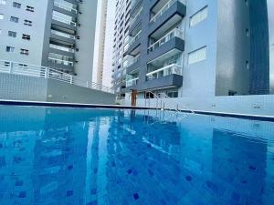 a large blue swimming pool next to two tall buildings at Flat Unitá Homestay in Praia Grande +88 photos