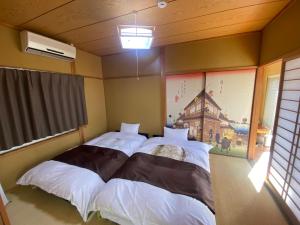 two beds in a room with a window at Yufu Inn in Yufuin