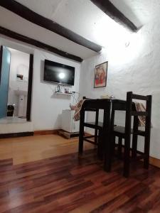 a dining room with a table and a tv on the wall at Asiriq Wasi Casita de huéspedes in Cusco