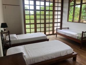 a room with three beds and windows at Casa de Campo in Rurrenabaque