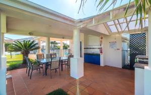 a conservatory with a table and chairs on a patio at Oceania Peace in Yamba