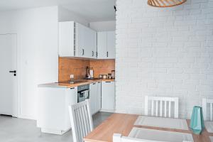 a kitchen with white cabinets and a white brick wall at Apartament na Wzgórzu 4 Sauny, ebike, las, widok - 5D Apartamenty in Świeradów-Zdrój