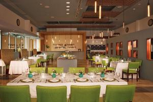 a dining room with white tables and green chairs at Altitude at Krystal Grand Cancun - All Inclusive in Cancún