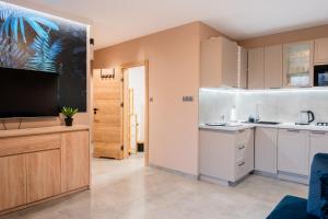 a kitchen with white cabinets and a flat screen tv at Apartament na Wzgórzu 2, Sauny, ebike, las, widok- 5D Apartamenty in Świeradów-Zdrój