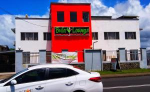 a white car parked in front of a red building at Sunseekers Outrigger Hotel in Suva