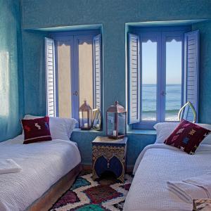 Habitación azul con 2 camas y ventanas con vistas al océano en TEDDY PIRATE - Coliving en Taghazout