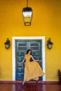 une femme en robe jaune debout devant une porte dans l'établissement Hacienda San Miguel Yucatan, à Valladolid