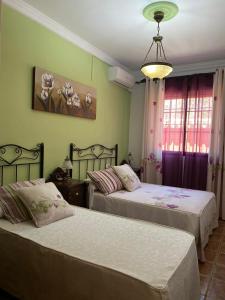 a bedroom with two beds and a chandelier at Casa Rural LA ENCINA in Hornachuelos