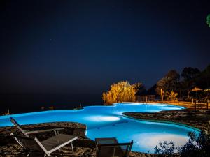 a swimming pool at night with two lounge chairs at Hotel Costa dei Fiori in Santa Margherita di Pula