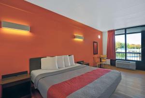 a hotel room with a bed with an orange wall at Motel 6-Seaford, DE in Seaford