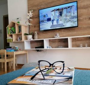 a pair of glasses sitting on a table with a television at Sunny Apartman 2 in Zlatibor