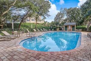 uma piscina com cadeiras, mesas e árvores em Sailmaker em Fernandina Beach