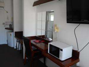 - un four micro-ondes installé sur un bureau en bois avec une chaise dans l'établissement Molly Morgan Motor Inn, à Maitland