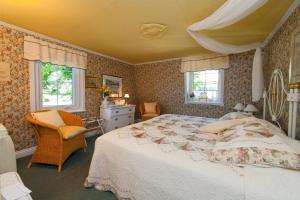 a bedroom with a large bed and two windows at Maison Victoria in La Malbaie