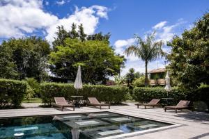 a pool with two chairs and a table with umbrellas at Pousada Celeiro do Gutto in Cunha