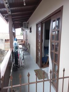 un hombre parado en el balcón de una casa en Hospedom Mazzoca 01, WC compartilhado, en Itapema
