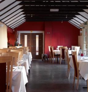 a dining room with tables and chairs and red walls at The Boleyn Hotel in Staines
