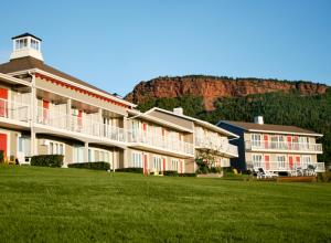 un grand bâtiment avec une montagne en arrière-plan dans l'établissement Hôtel le Mirage, à Percé