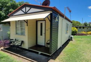 una casa pequeña con una mesa y sillas en un patio en Mt Larcom Tourist Park en Mount Larcom