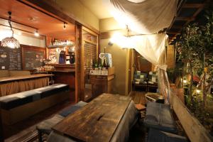 un restaurante con una mesa de madera y un bar en Roku Hostel Hiroshima, en Hiroshima