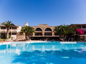 
a large swimming pool in front of a large building at Hotel Costa dei Fiori in Santa Margherita di Pula
