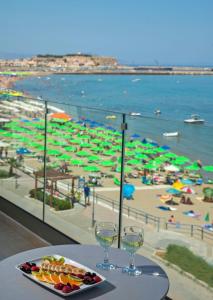 una mesa con un plato de comida y copas de vino en una playa en Swell Boutique Hotel, en Rethymno